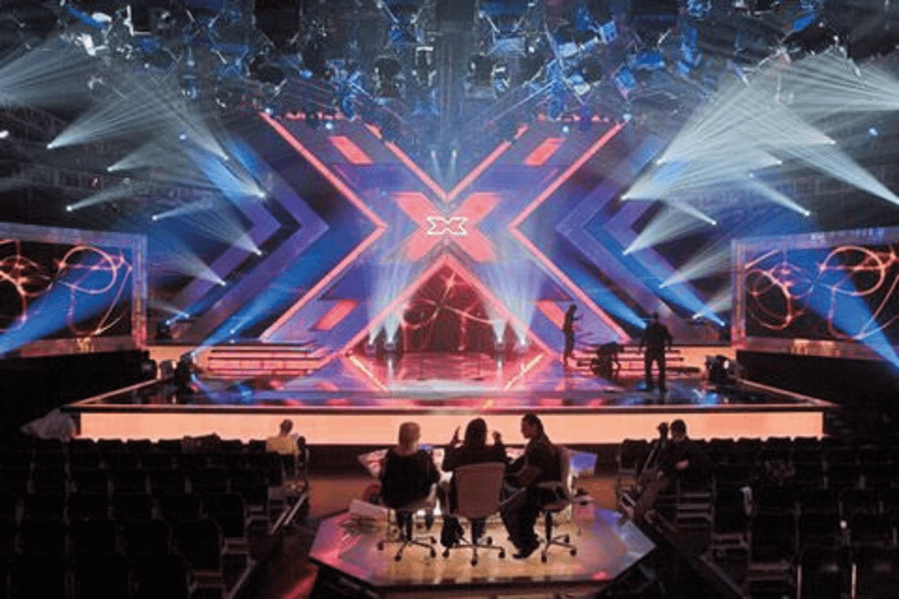 Large stage with X-shaped LED backdrop and theatrical lighting